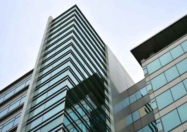 Low angle view of a modern skyscraper with glass facade reflecting the sky.